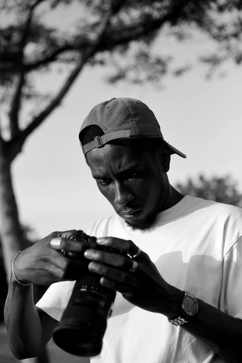 Focused photographer adjusting his camera outdoors in Abuja, Nigeria.