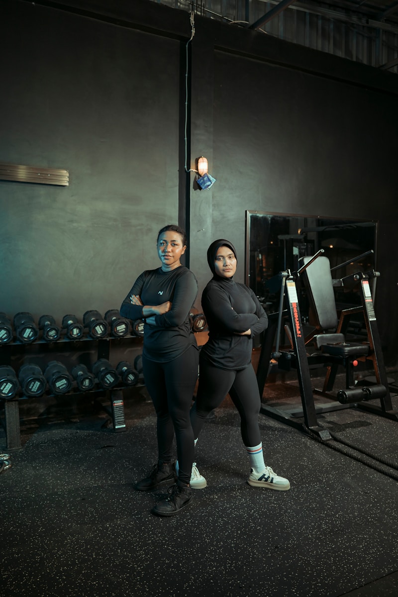 Two women pose proudly in a gym.